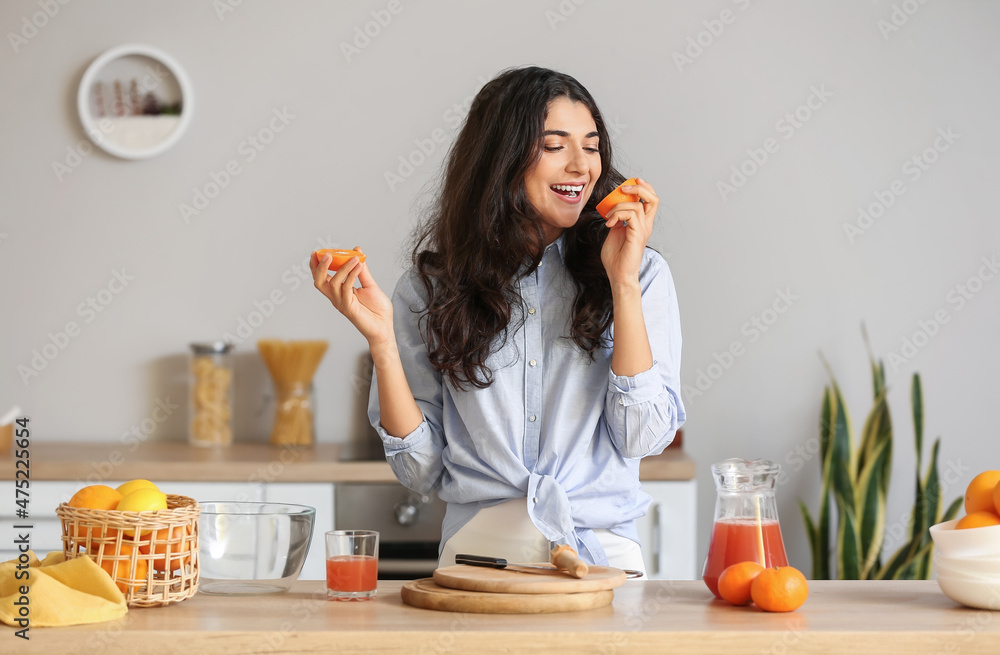 年轻女子在厨房制作新鲜柑橘汁