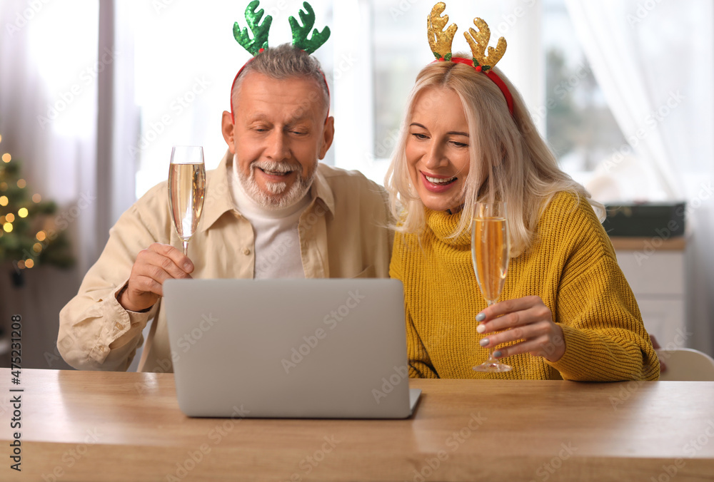 Happy mature couple video chatting at home on Christmas eve