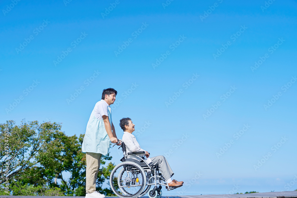 介護士と車椅子に乗る高齢者　屋外