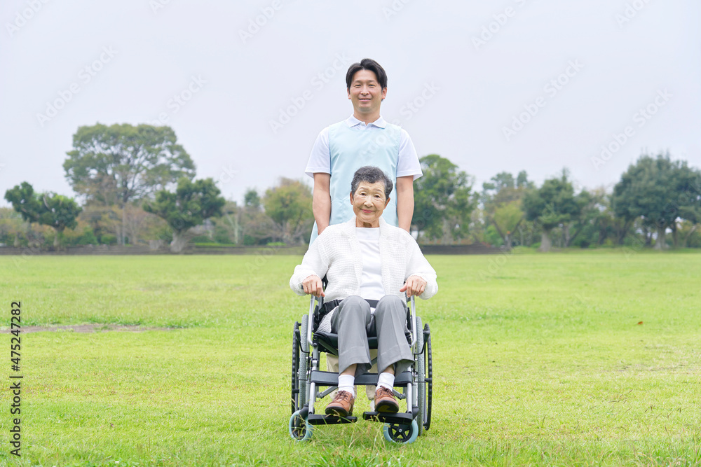 介護士と車椅子に乗る高齢者　屋外