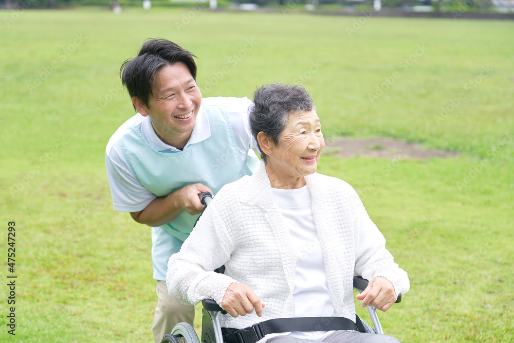 介護士と車椅子に乗る高齢者　屋外