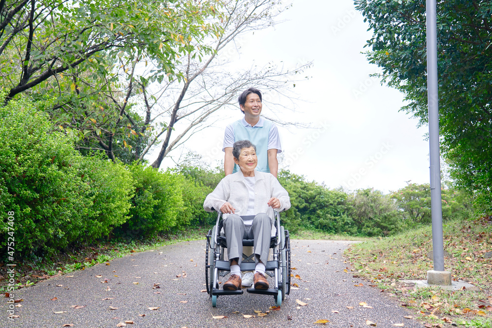 介護士と車椅子に乗る高齢者　屋外