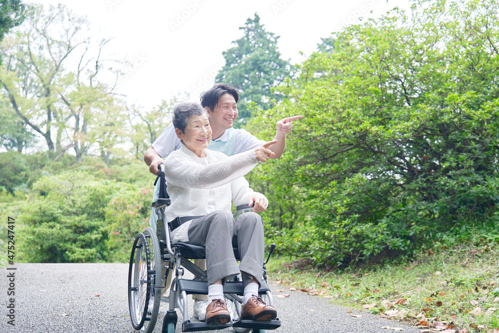 介護士と車椅子に乗る高齢者　屋外