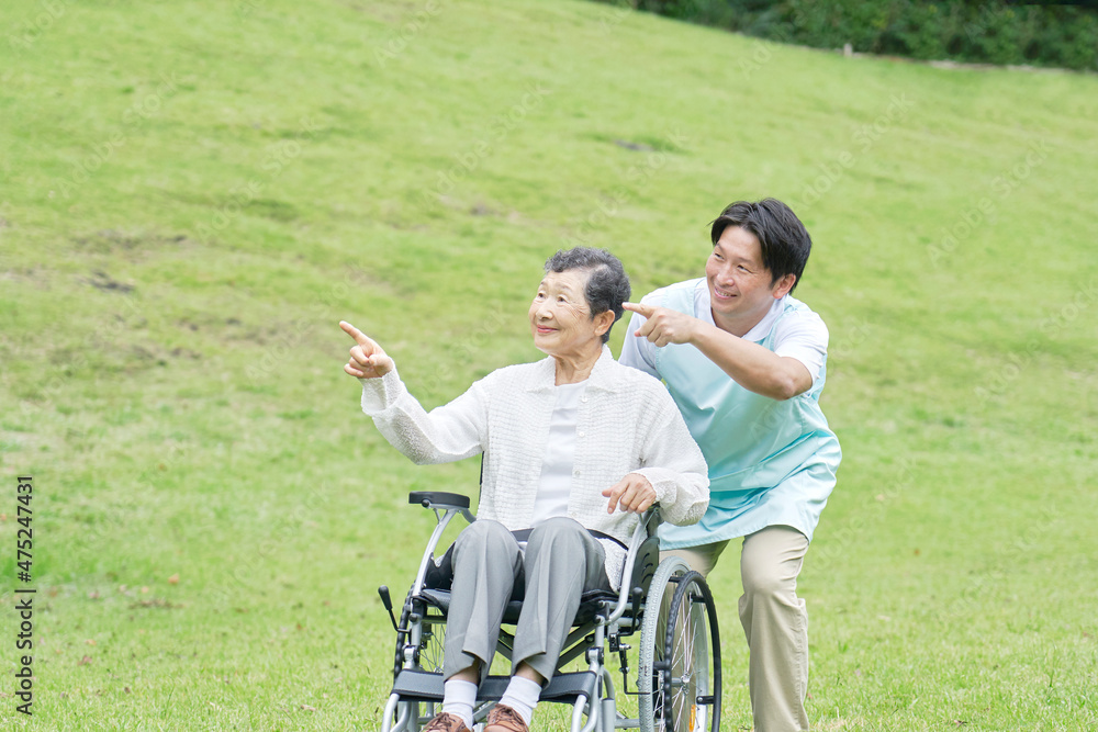 介護士と車椅子に乗る高齢者　屋外