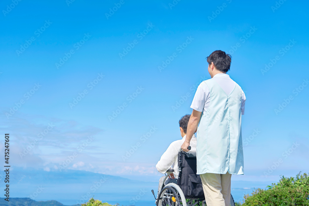 介護士と車椅子に乗る高齢者　屋外