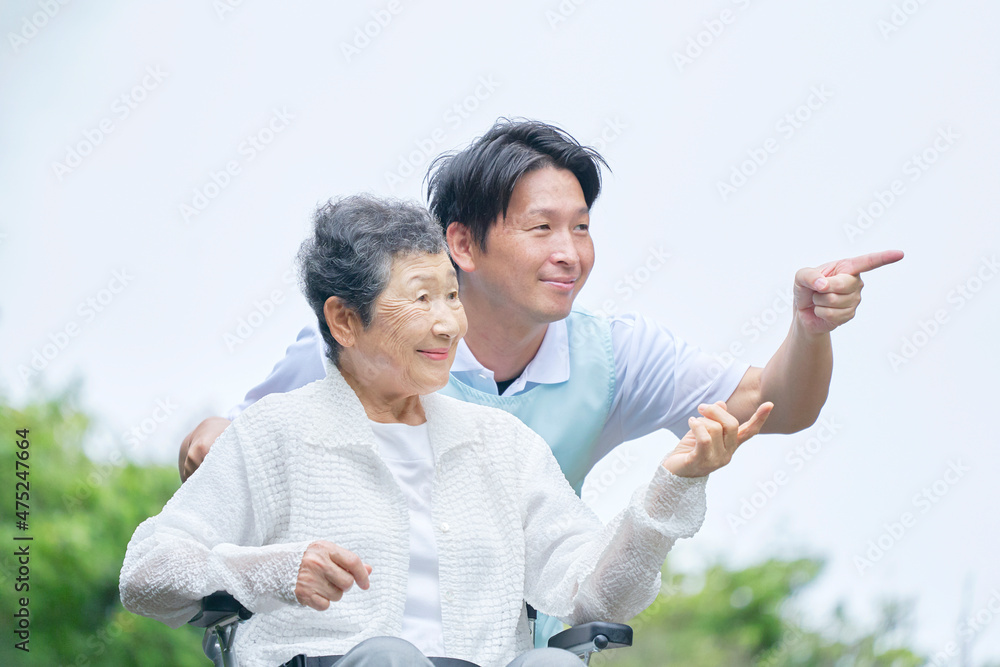 介護士と車椅子に乗る高齢者　屋外