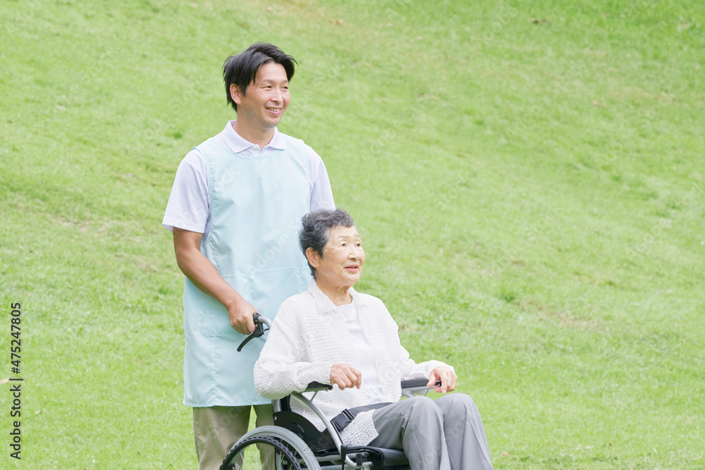 介護士と車椅子に乗る高齢者　屋外