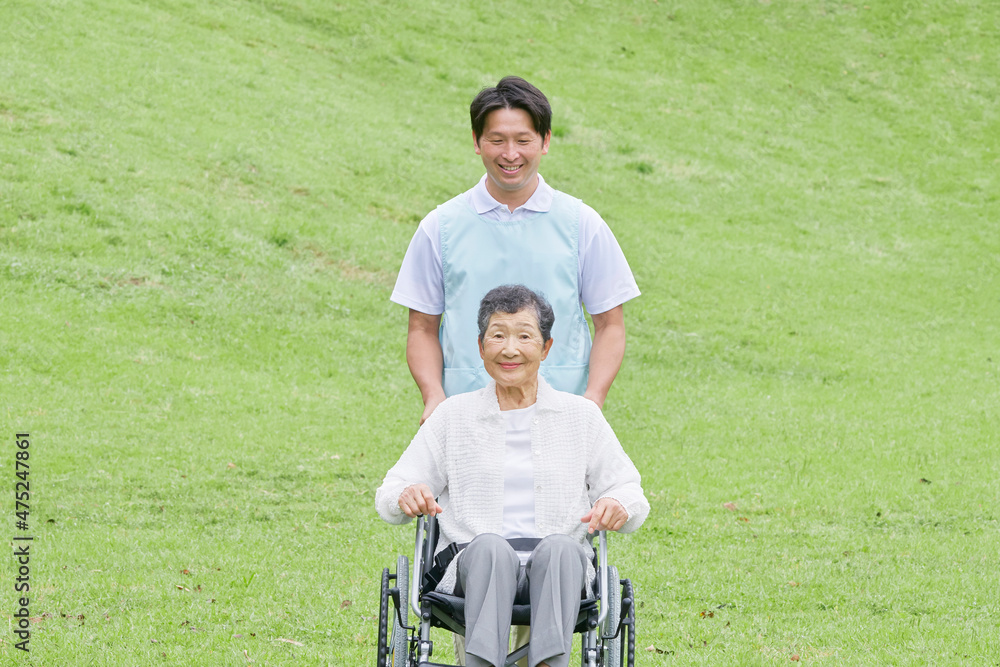 介護士と車椅子に乗る高齢者　屋外