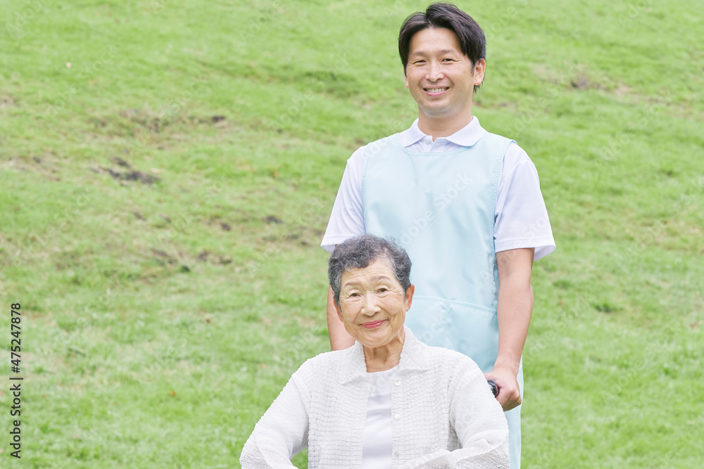 介護士と車椅子に乗る高齢者　屋外