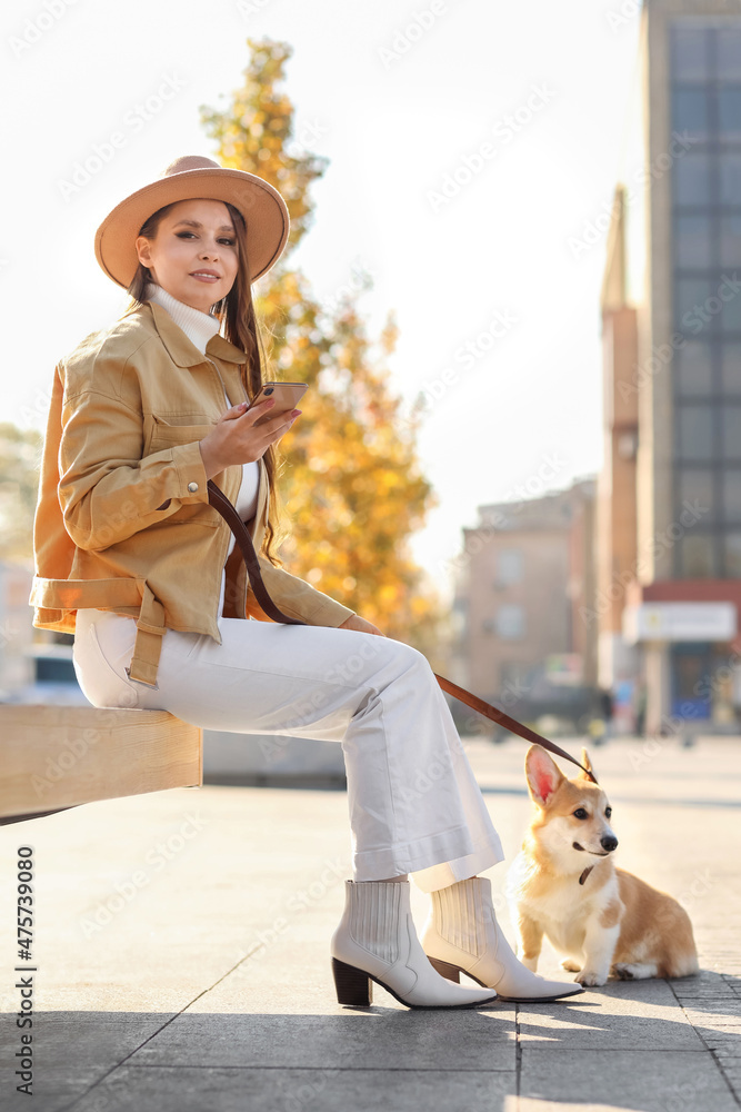 年轻女子在城市广场上牵着可爱的柯基犬