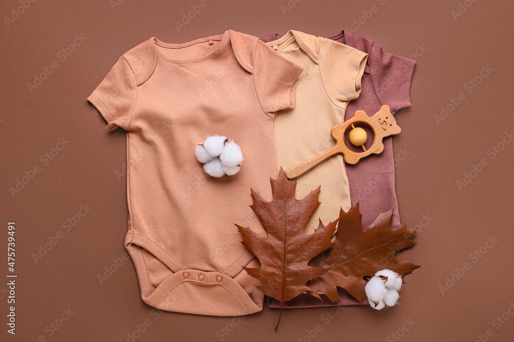 Set of baby clothes, toy, cotton flowers and autumn leaves on color background