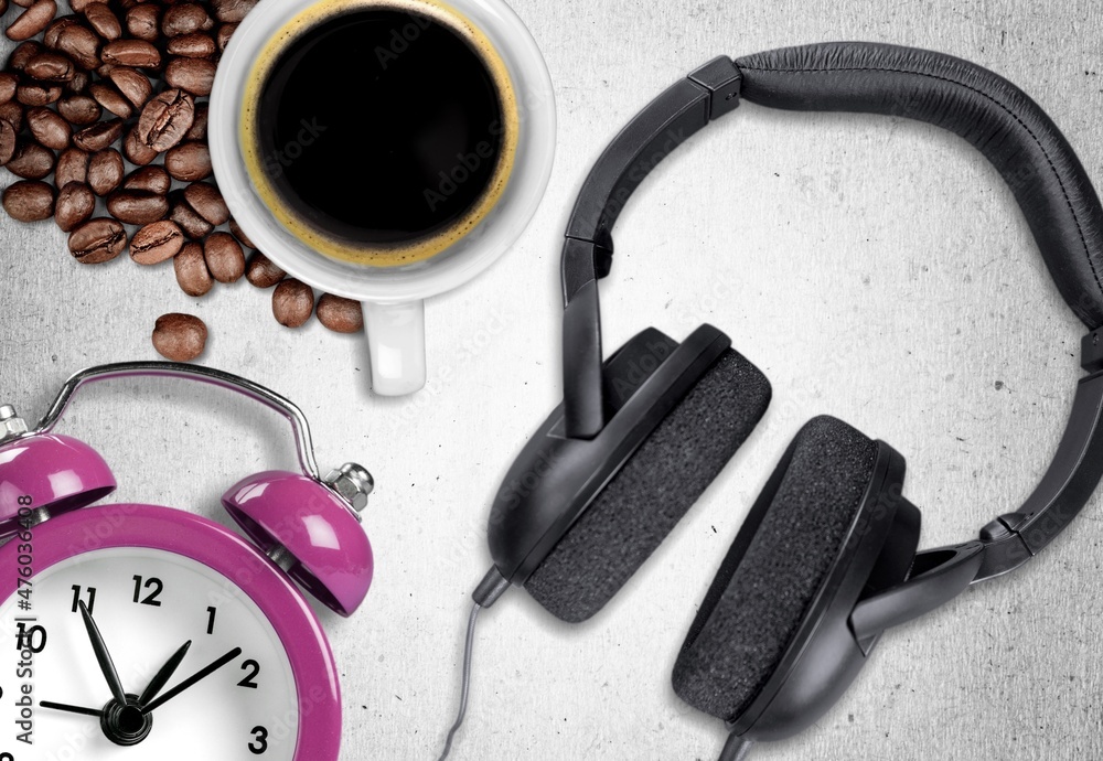 Hot coffee mug with headphones in vintage style and coffee beans on the desk.