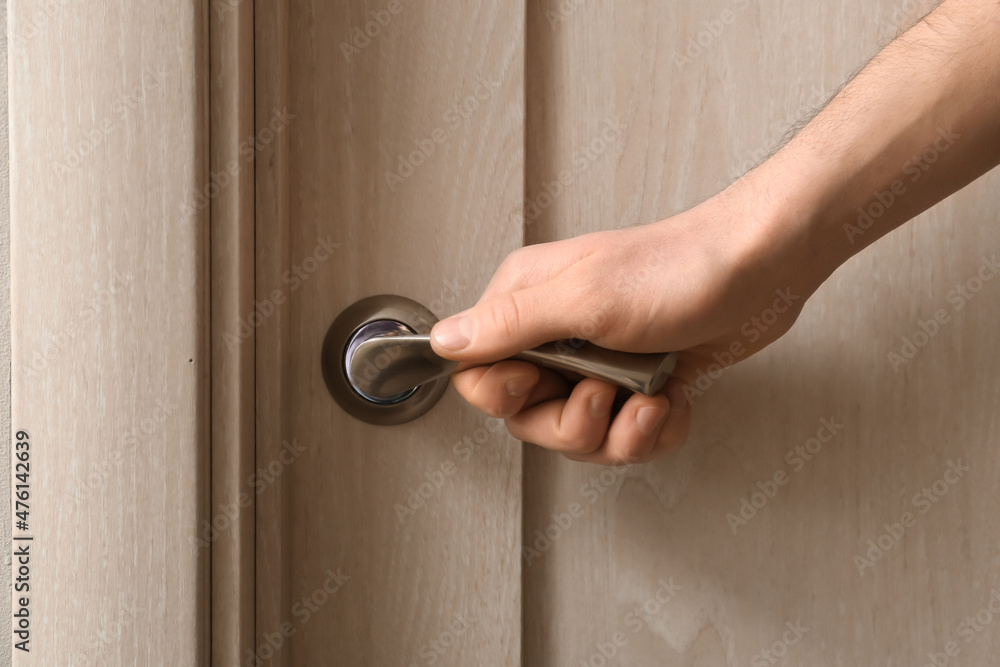 Man opening light wooden door at home, closeup