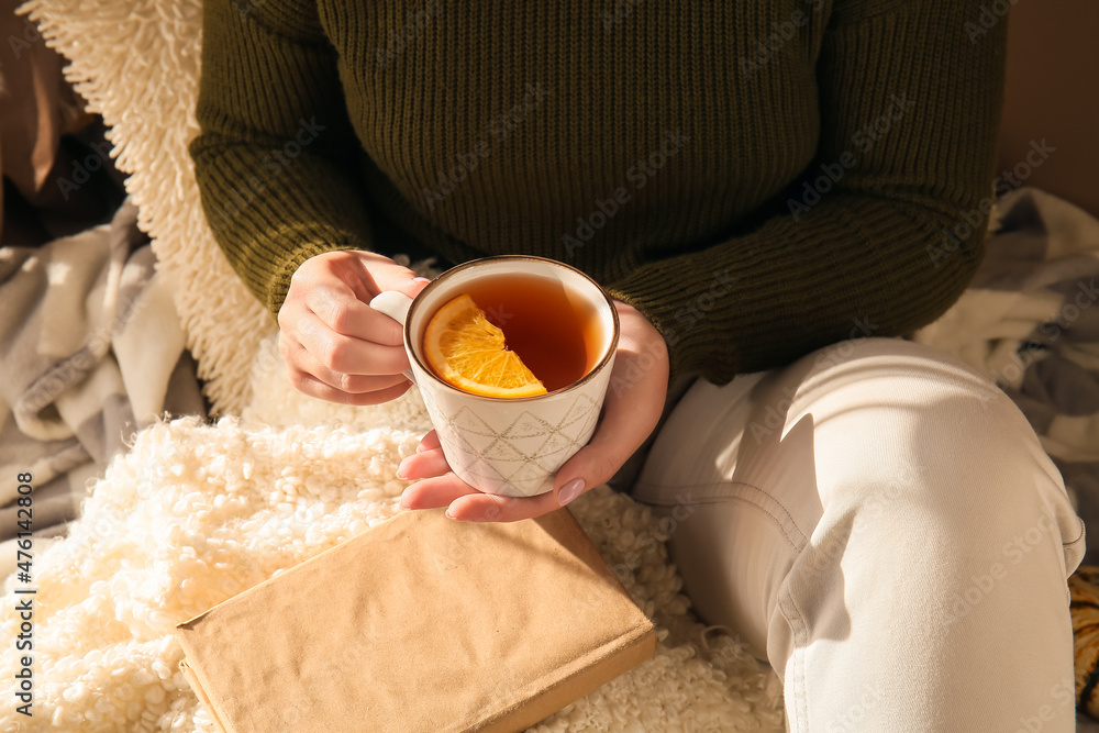 女人拿着一杯美味的茶和一片柑橘类水果，特写镜头