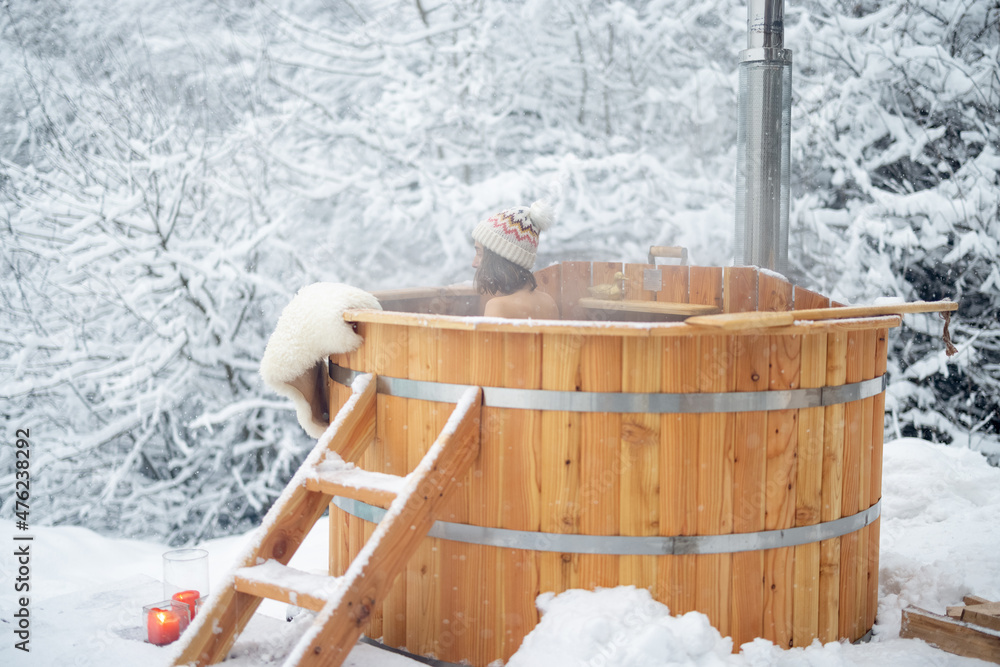 女人在户外洗热水澡放松，在雪山享受温泉。冬季假期在