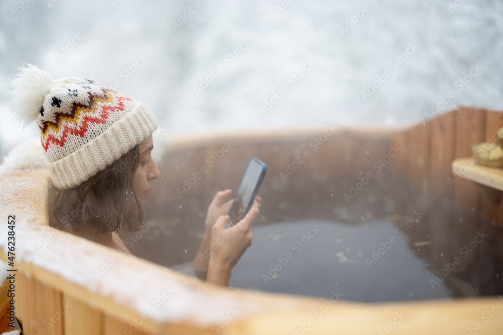 女人在户外洗热水澡放松，在雪山享受温泉。冬季娱乐和