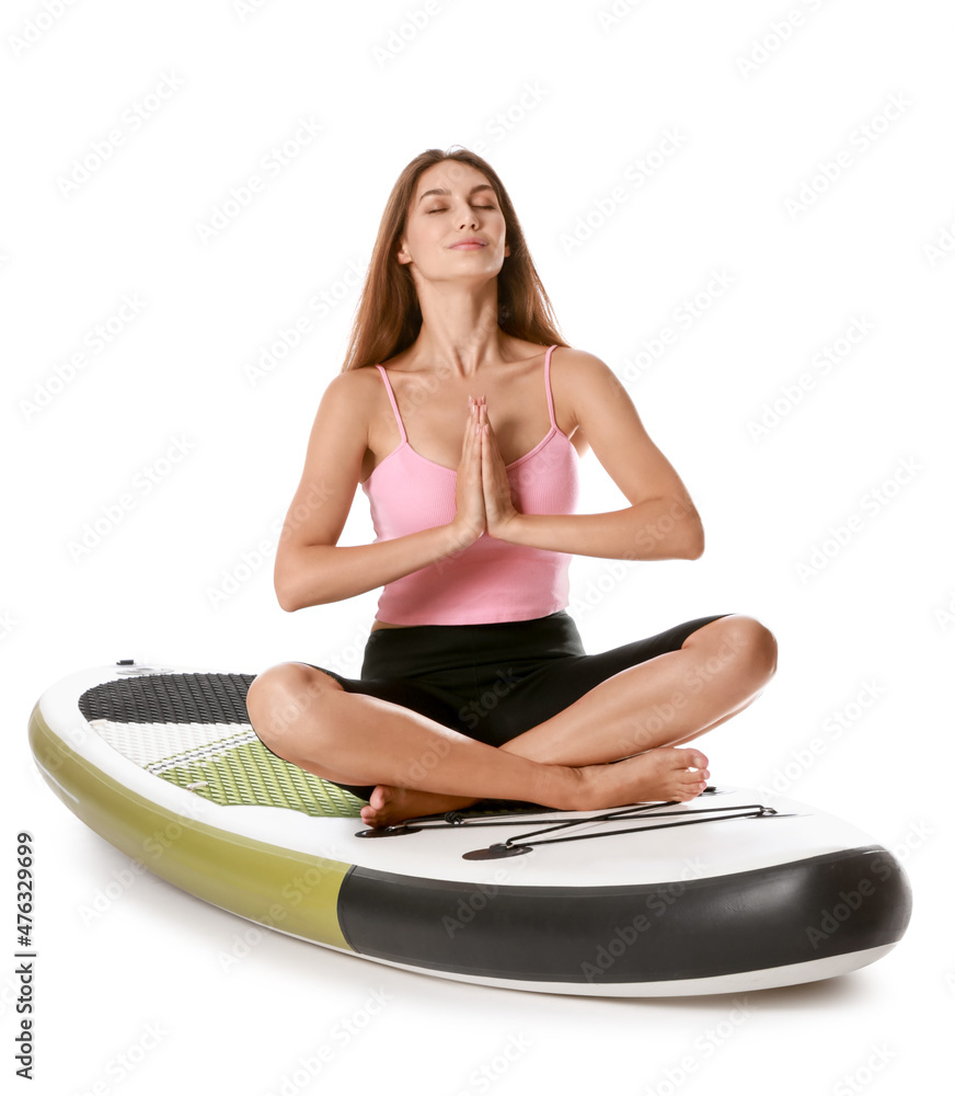 Young woman meditating on sup board on white background