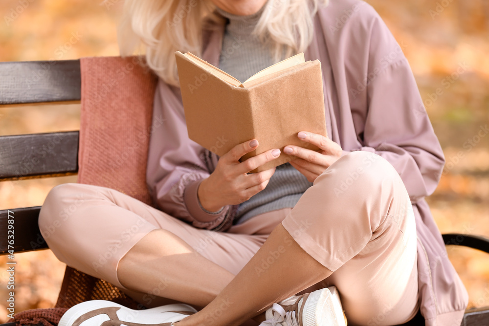 Mature woman reading book in autumn park