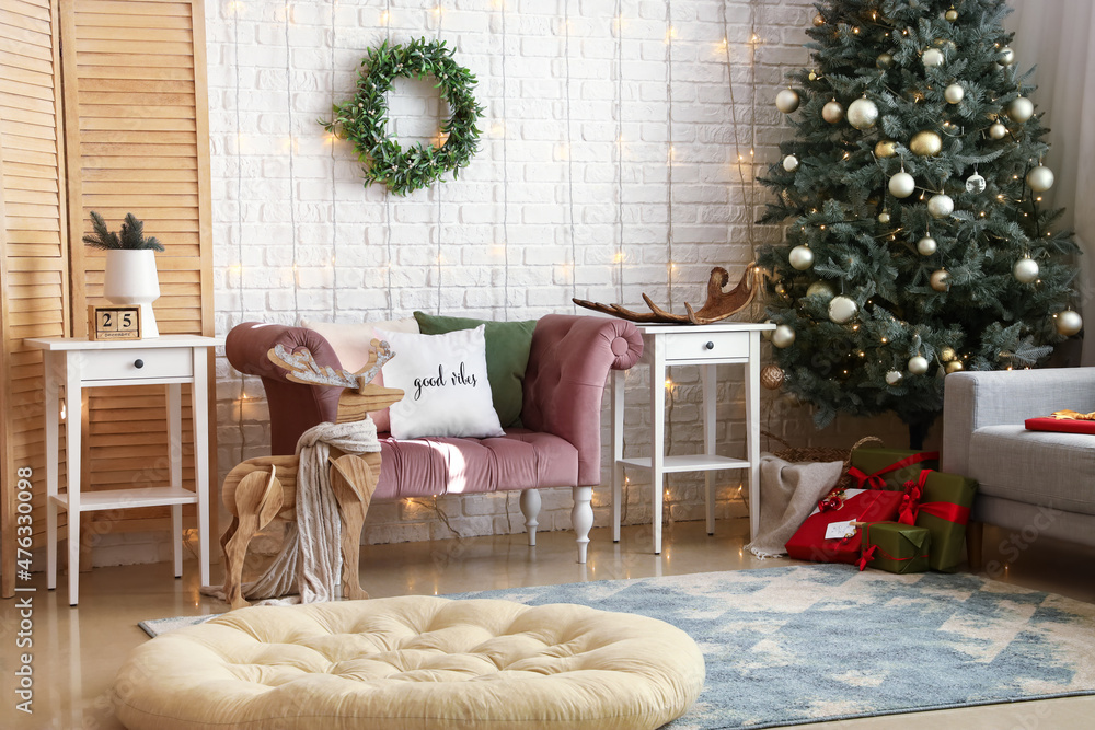 Interior of stylish living room with pink armchair, Christmas tree and glowing lights