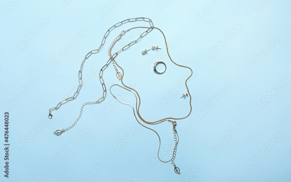 Female face made of stylish golden jewelry on color background