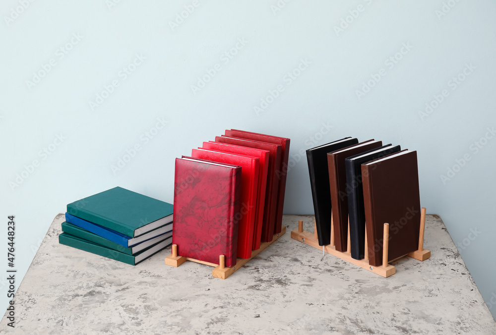 Organizers with books on table near color wall