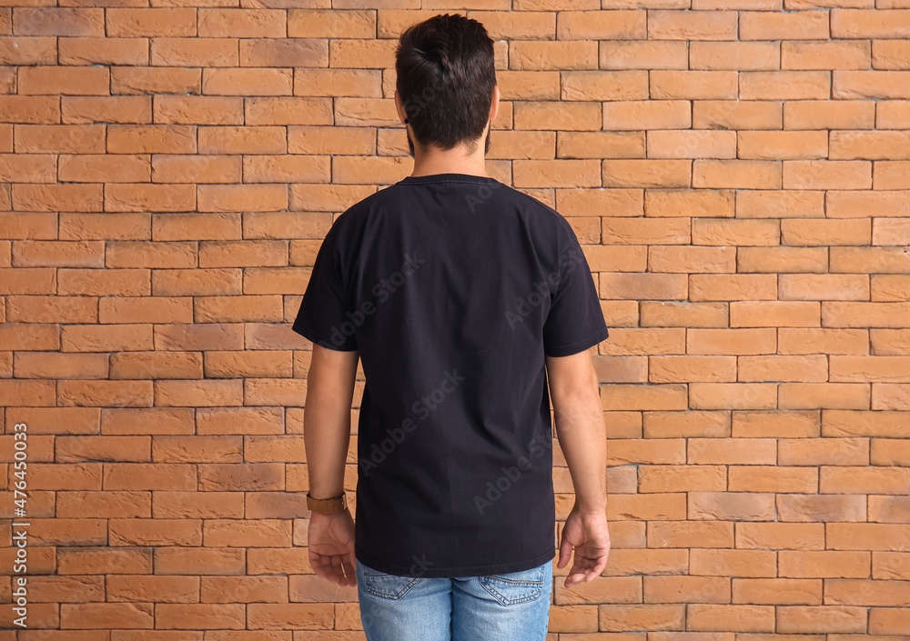 Handsome man in black t-shirt on brick background