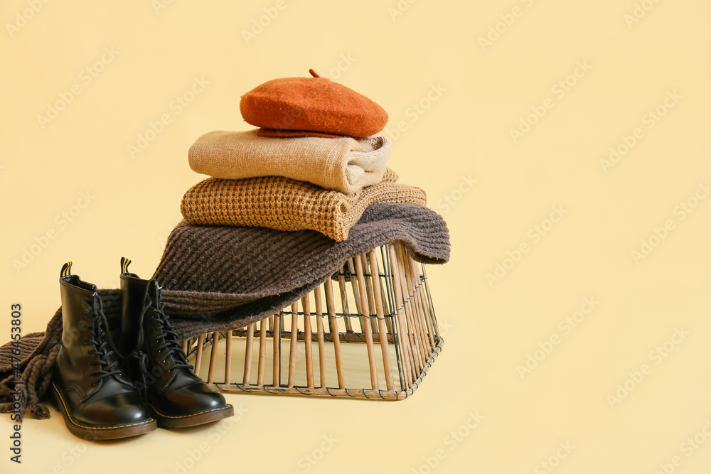 Basket with stylish winter clothes on light background