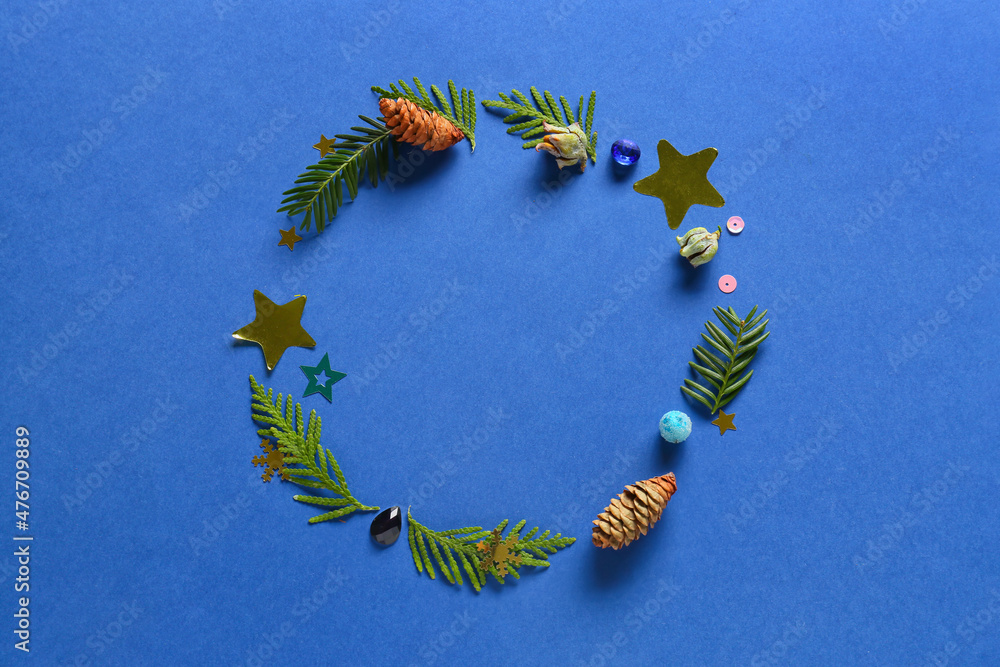 Frame made of fir branches, cones and Christmas decor on blue background