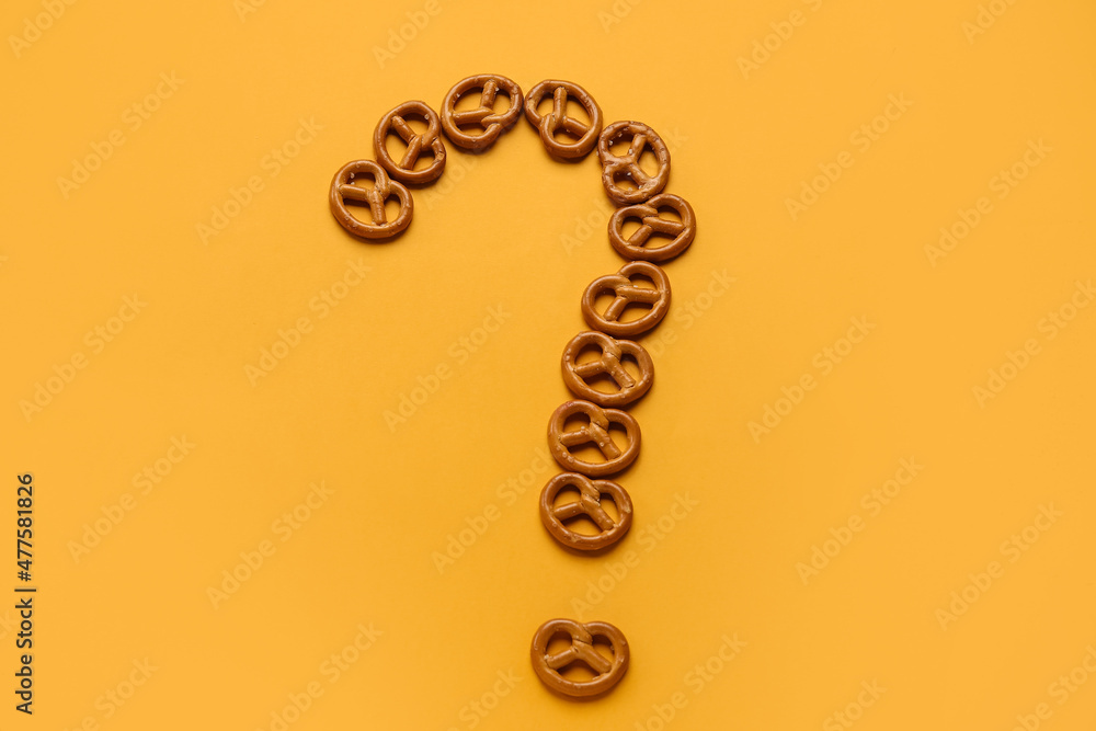 Question mark made of mini pretzels on orange background