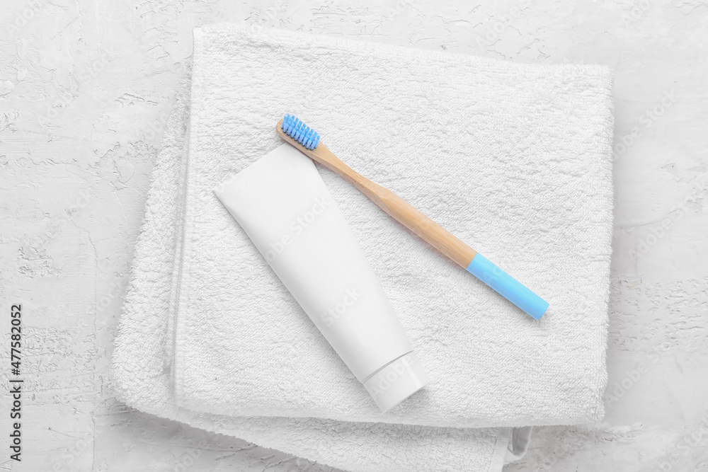 Bamboo tooth brush with paste and towel on white background