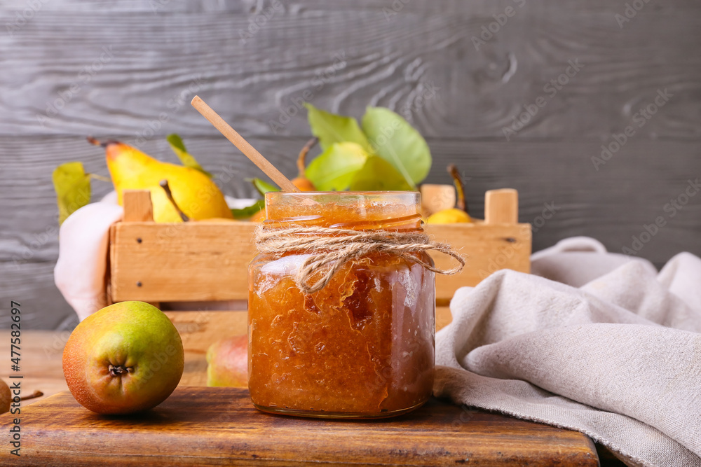 Glass jar of tasty pear jam on table