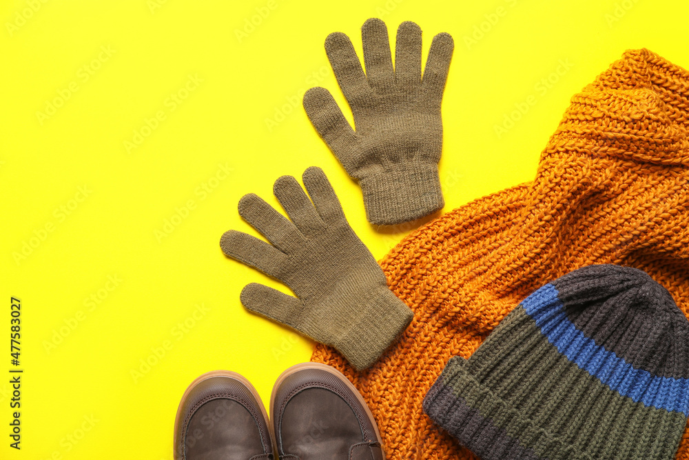 Warm gloves, hat and shoes on color background, closeup