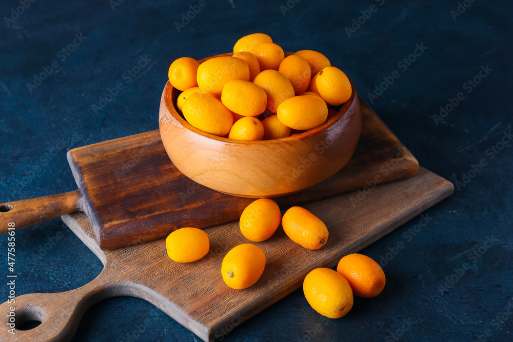 Bowl with tasty kumquat fruits on dark background