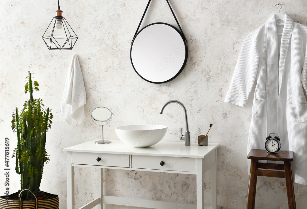 Interior of light room with sink, cactus and bathrobe