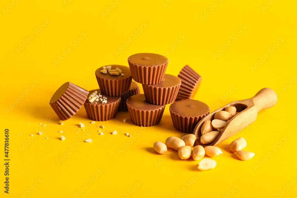 Tasty peanut butter cups on color background