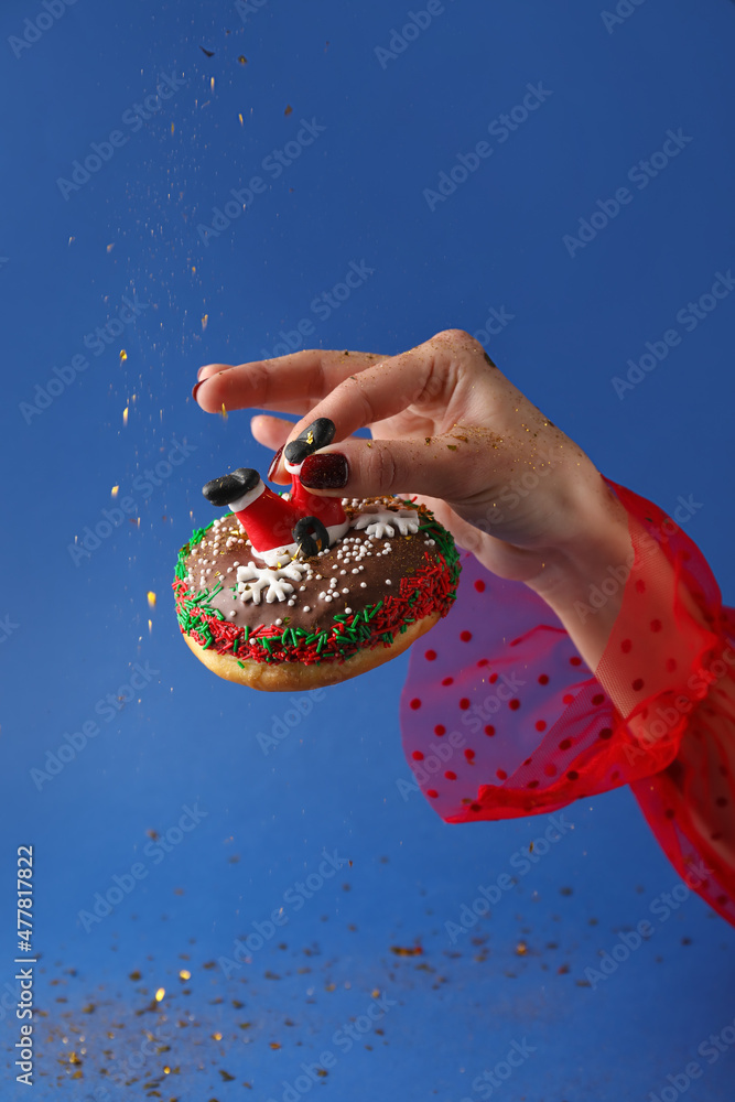 Woman holding tasty Christmas donut on blue background