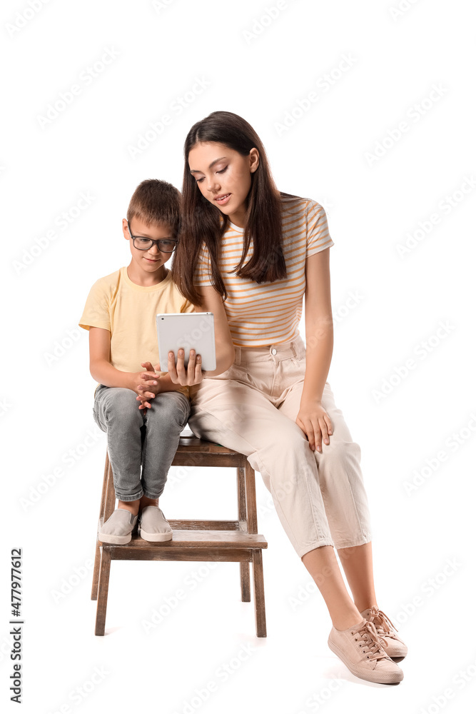 Little boy with his older sister using tablet computer on white background