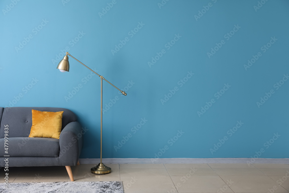 Golden standard lamp and sofa near blue wall