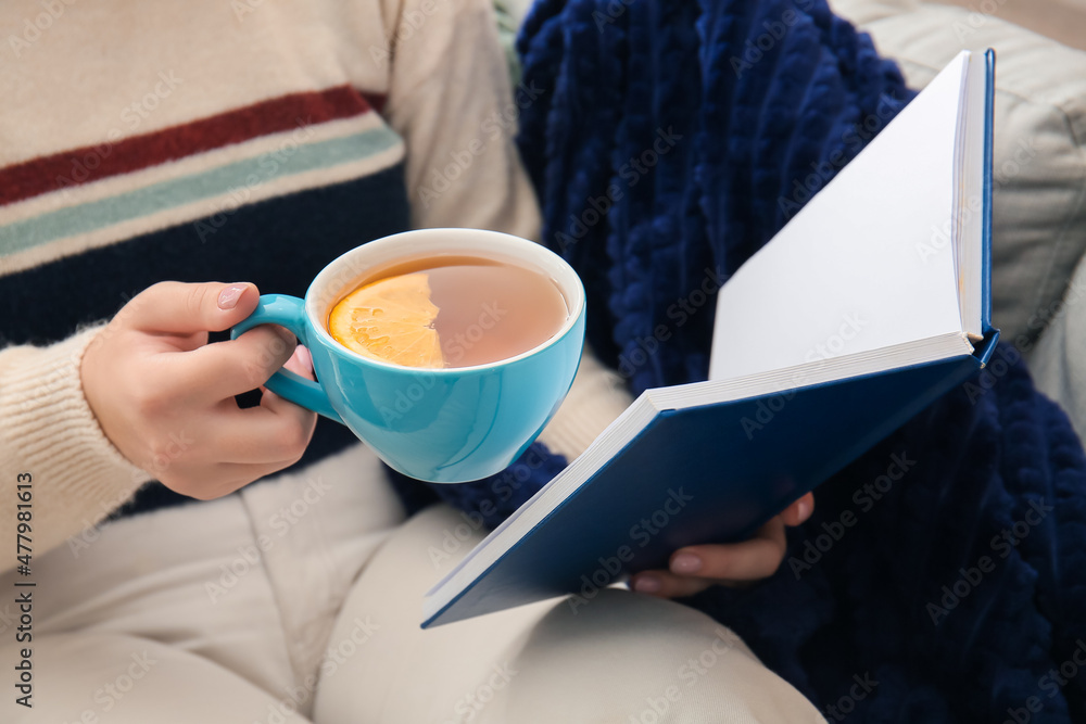 Woman drinking tea and reading book, closeup