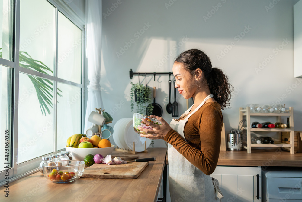 拉丁裔美女系围裙在家厨房做绿色沙拉