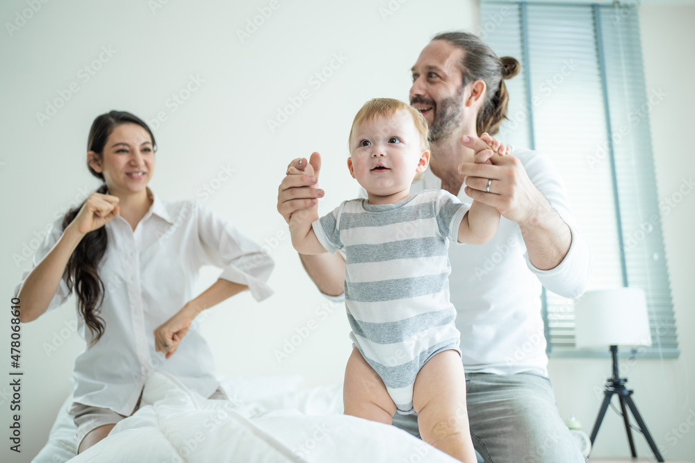 爱高加索的父母在卧室的床上和男婴玩耍。