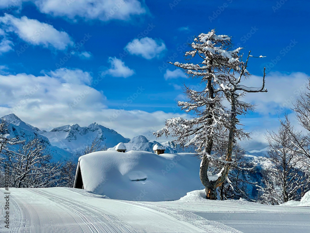 空旷整洁的滑雪场斜坡经过阿尔卑斯山一座被新雪覆盖的小屋