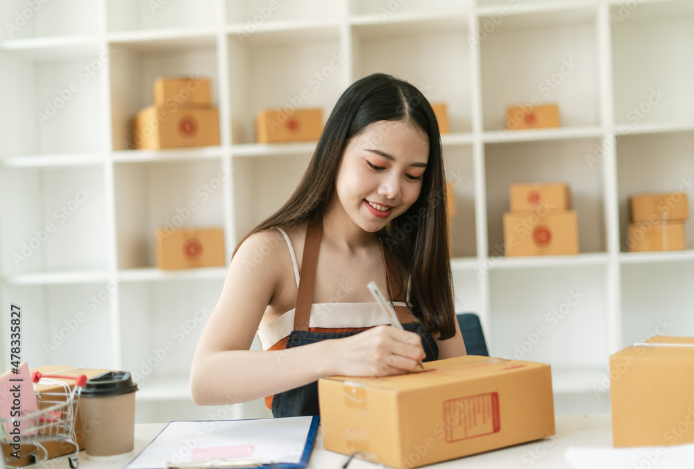 Young Asian small business owner happy with his ecommerce business preparing parcel for her online o