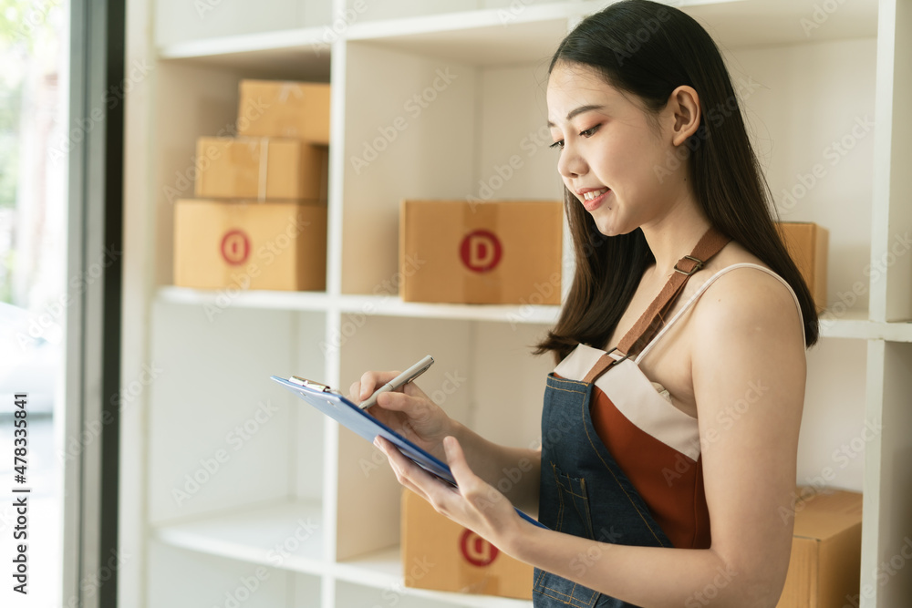 Young woman freelancer working and checklist and writing order with cardboard box ,SME business onli