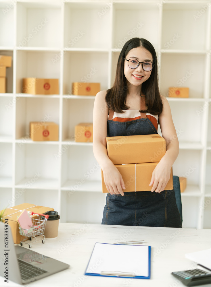 Young Asian small business owner happy with his ecommerce business preparing parcel for her online o