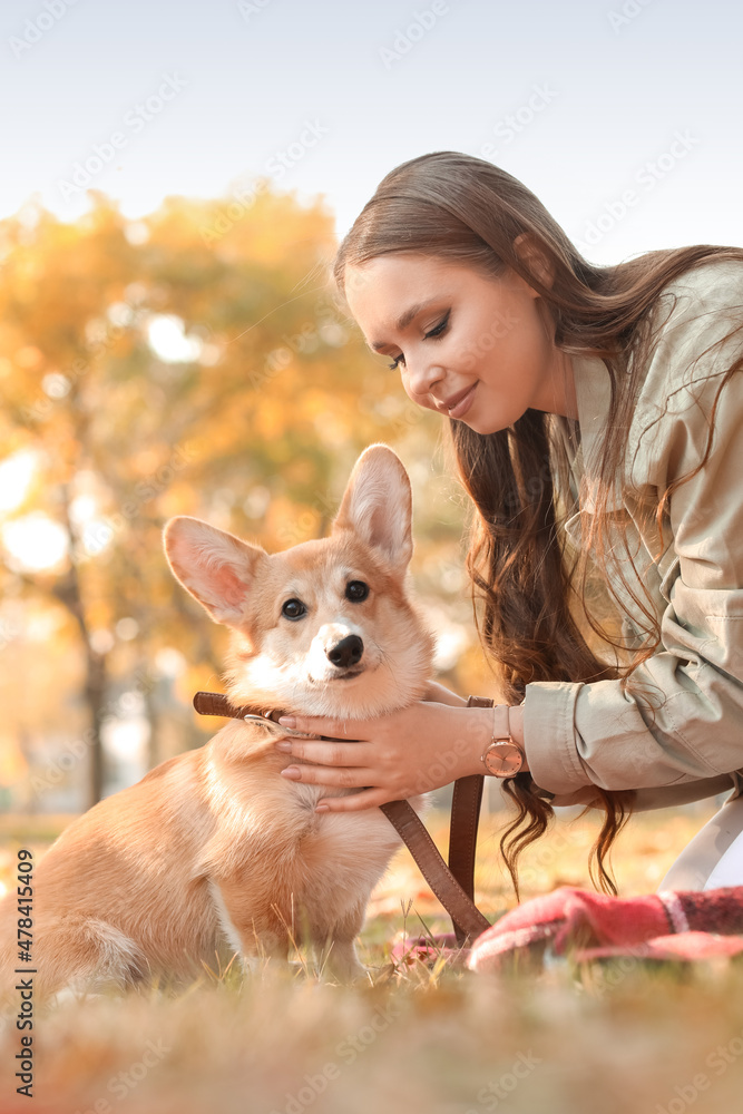 年轻女子带着可爱的柯基犬在秋季公园