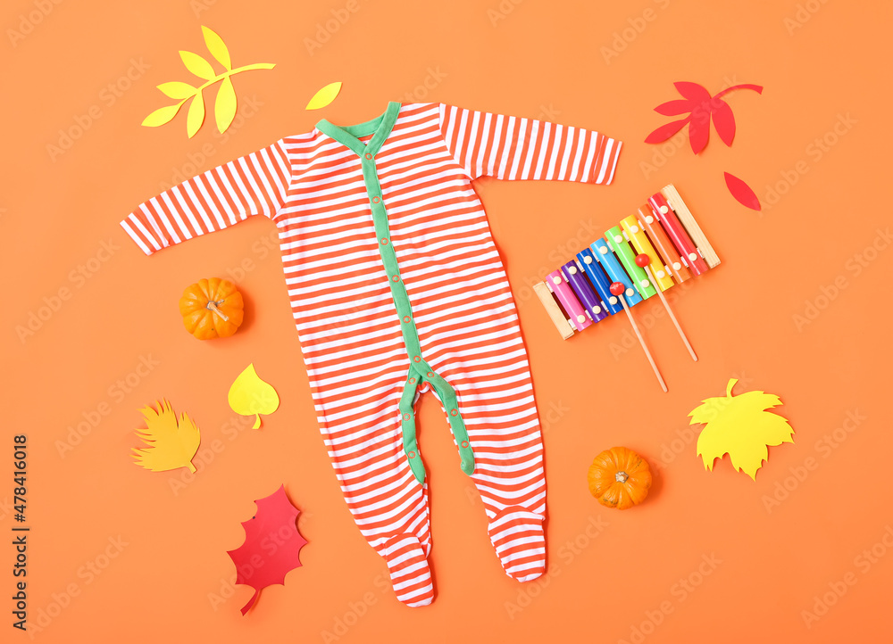 Baby bodysuit, xylophone and autumn decor on color background