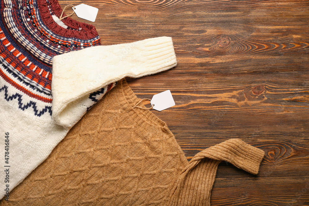 Knitted sweaters and price tags on wooden background