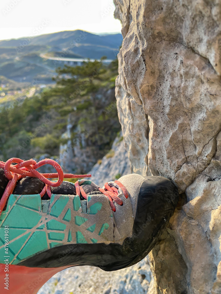 特写：登山者踩在小石壁上时，穿着攀岩鞋的镜头。