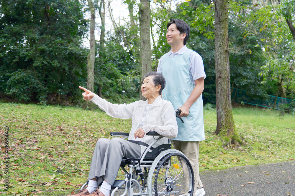 介護士と車椅子に乗る高齢者　屋外